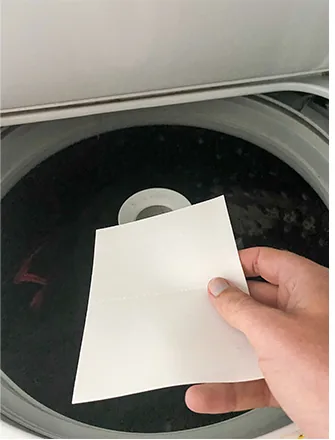 Dropping a detergent sheet into the washing machine drum with the clothes